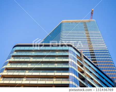 A newly built house. Glazed skyscraper. Reflection of the sky in the windows. Multi-apartment modern housing. A newly built house. Glazed skyscraper. Reflection of the sky in the windows. Multi-apartment modern housing. 131436769