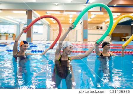 Group of female athletes exercising with aqua sticks 131436886