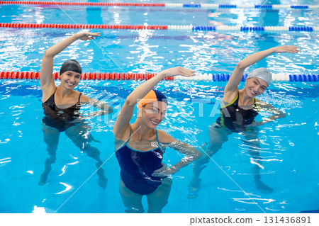 Women exercising together in indoor swimming pool Women exercising together in indoor swimming pool 131436891