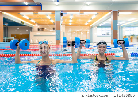 Swimmers exercising with aqua weights in indoor pool Swimmers exercising with aqua weights in indoor pool 131436899