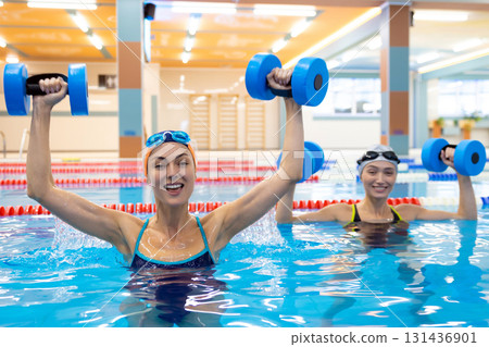 Women training with water dumbbells in swimming pool Women training with water dumbbells in swimming pool 131436901