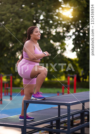 Young woman in pink sportswear exercising at the sports ground Young woman in pink sportswear exercising at the sports ground 131436934