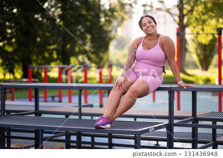 Young smiling woman in pink sportswear resting after a workout 131436948