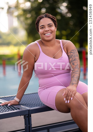 Young smiling woman in pink sportswear resting after a workout 131436949