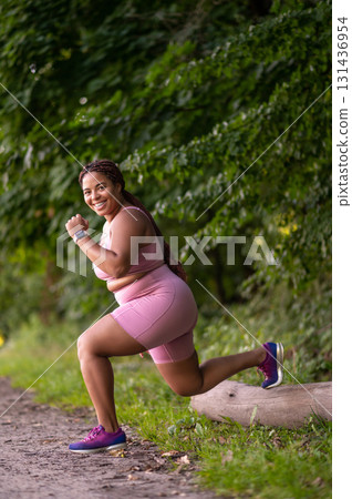African american plus size young woman exercising in the forest and looking determined African american plus size young woman exercising in the forest and looking determined 131436954