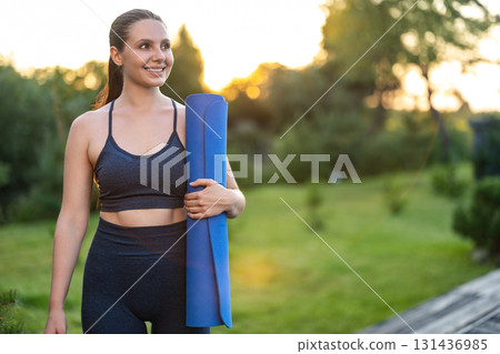 Cute young girl with a yoga mat walking in the park Cute young girl with a yoga mat walking in the park 131436985