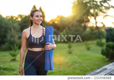 Cute young girl with a yoga mat walking in the park Cute young girl with a yoga mat walking in the park 131436988