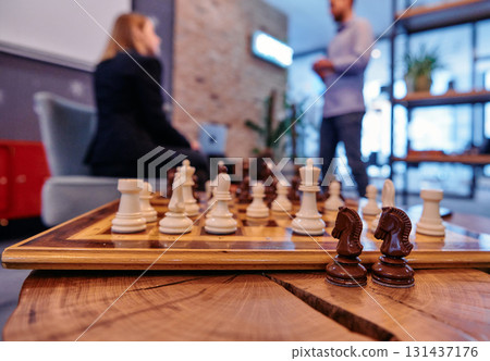 Strategic Moves: A Close Up of Chess Pieces Symbolizing Business Tactics Amidst Team Discussions. 131437176