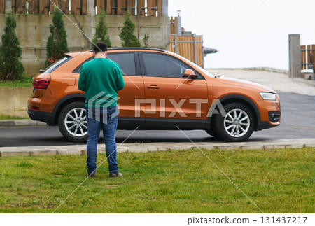 Capturing the Moment: A Man Photographs His Car for Sale to Share Online 131437217