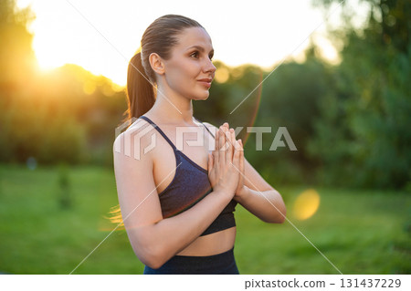 Waist up of a young woman standing with her hands in namaste 131437229