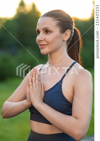 Waist up of a young woman standing with her hands in namaste 131437231