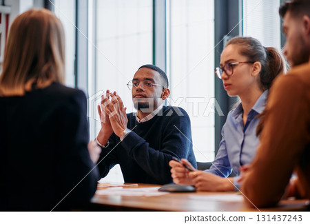 In the vibrant ambiance of a modern startup office, a diverse team of business professionals engage in discussions on various projects and develop new business strategies, epitomizing creativity and 131437243