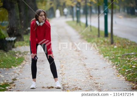 Athletic young woman taking a breath and relaxing after jogging and stretching. Woman Training and Workout Exercises On Street. 131437254