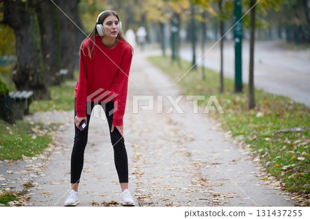 Athletic young woman taking a breath and relaxing after jogging and stretching. Woman Training and Workout Exercises On Street. 131437255