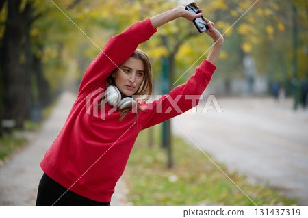 Athletic young woman taking a breath and relaxing after jogging and stretching. Woman Training and Workout Exercises On Street. Athletic young woman taking a breath and relaxing after jogging and stretching. Woman Training and Workout Exercises On Street. 131437319