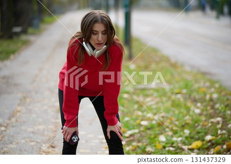 Athletic young woman taking a breath and relaxing after jogging and stretching. Woman Training and Workout Exercises On Street. 131437329