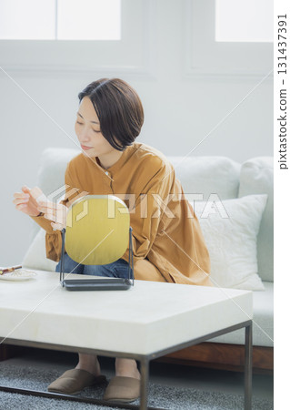 A woman looking in the mirror in the living room A woman looking in the mirror in the living room 131437391