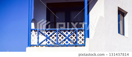 White painted house with wooden blue balcony and windows frame. 131437814