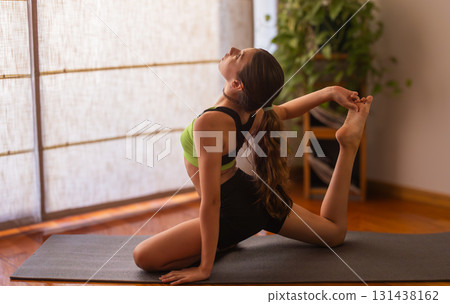 Young girl stretching in serene indoor space. Blurred background. Natural light 131438162