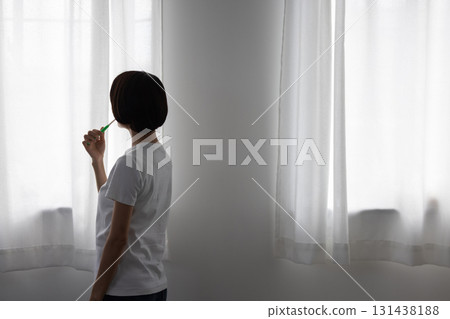 Middle-aged woman brushing her teeth by the window 131438188