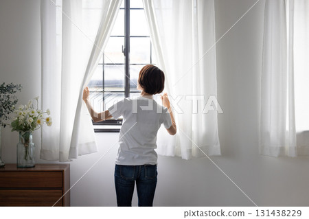 The back of a woman who opens a curtain 131438229