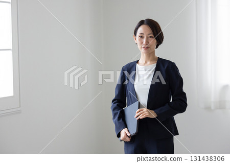 A middle-aged woman in a suit walking indoors 131438306