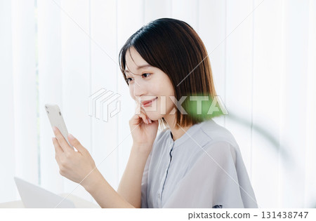 Business woman looking at a smartphone in the office Business woman looking at a smartphone in the office 131438747