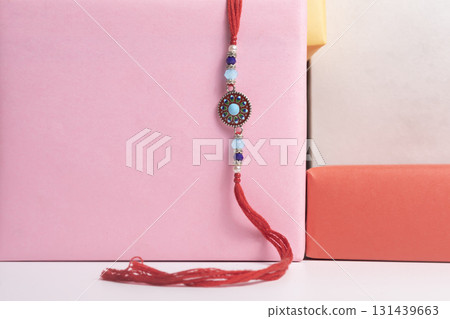 Handmade bead bracelet wrapped in red thread on top of a pink gift box for celebration. 131439663