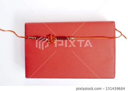 Red gift box with a soft beaded bracelet wrapped in orange thread for gift giving on Raksha Bandhan. Red gift box with a soft beaded bracelet wrapped in orange thread for gift giving on Raksha Bandhan. 131439684