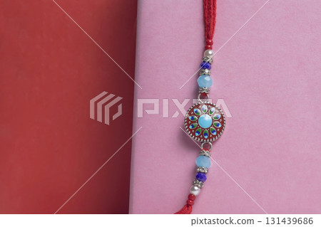 Close-up colorful beaded bracelet with a turquoise pendant on a pink background for Raksha Bandhan 131439686