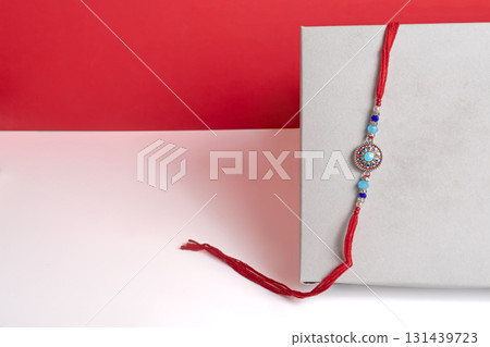 Elegant red thread rakhi with gemstone beads on a modern background 131439723