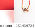 Intricately designed rakhi with beads on vibrant red background for the festive season. 131439724