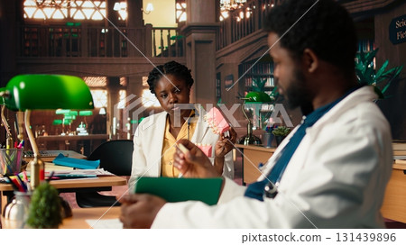 African American dentistry students examining teeth for upcoming exams, learning session on caries prevention using a jaw model in a library. Dedication to oral health education. Camera A. 131439896