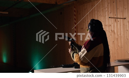 Cheerful woman in shooting range trying out new gun model before committing to purchase. Happy person in firing range learning how to operate new weapon safely during self defense training, camera A Cheerful woman in shooting range trying out new gun model before committing to purchase. Happy person in firing range learning how to operate new weapon safely during self defense training, camera A 131439903