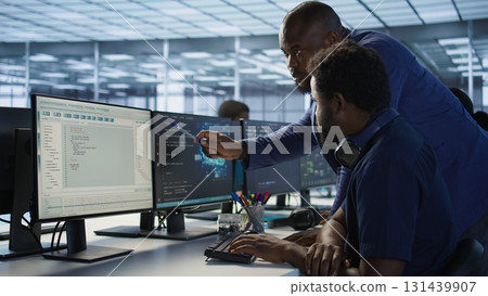 Manager assisting data center engineer in solving tasks, maintaining company network infrastructure. Team leader in server farm helping worker ensuring optimal system performance 131439907