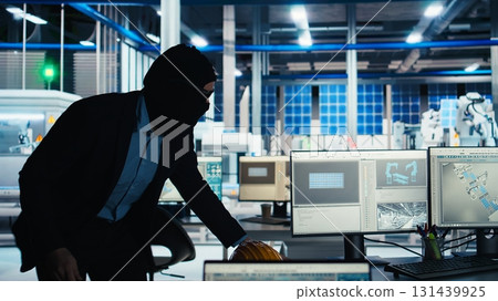 Hacker sneaking into solar panel facility, inserting USB stick into PC to steal secret manufacturing data. Thief bypasses photovoltaics factory security, extracting company files, camera A 131439925