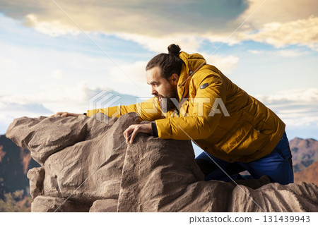 Reckless unprepared hiker stumbles near the edge of a high altitude cliff, caught off guard by strong winds. Unequipped for the extreme conditions, losing balance on mountain top. Reckless unprepared hiker stumbles near the edge of a high altitude cliff, caught off guard by strong winds. Unequipped for the extreme conditions, losing balance on mountain top. 131439943