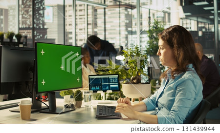 Green screen PC in office used by employee working on company administrative tasks. Mockup computer display on desk used by worker reviewing business data metrics, camera B 131439944