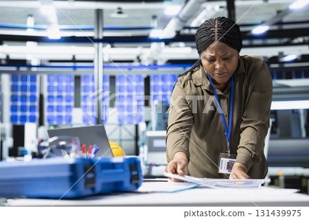 Female master engineer performing quality control on solar power production, showcasing cheaper renewable energy with infrastructure development. Industrial engineering in solar plant. Female master engineer performing quality control on solar power production, showcasing cheaper renewable energy with infrastructure development. Industrial engineering in solar plant. 131439975