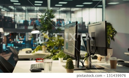 Business graphs and KPI metrics on displays in workplace, jib up shot. Office desk setup in bright corporate environment with computer screens displaying data analytics, close up shot 131439976