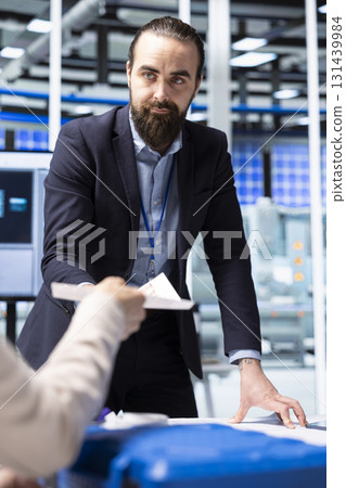 Factory management executives looking over paperwork documents, discussing solar panel automation strategies. Team analyzing documentation files data to enhance sustainable manufacturing processes 131439984