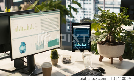 Business graphs and KPI metrics on displays in workplace, jib up shot. Office desk setup in bright corporate environment with computer screens displaying data analytics, close up shot Business graphs and KPI metrics on displays in workplace, jib up shot. Office desk setup in bright corporate environment with computer screens displaying data analytics, close up shot 131440009