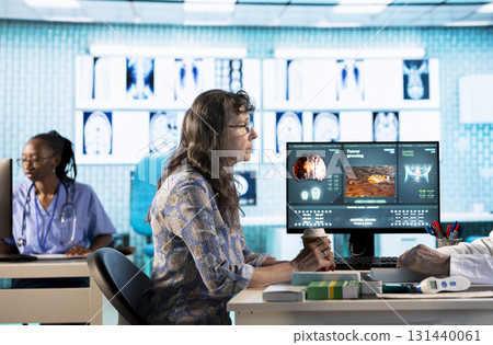Senior physician meeting with female patient to discuss results in a cabinet, using advanced diagnostic equipment to interpret x ray scans and results, professional healthcare approach. 131440061