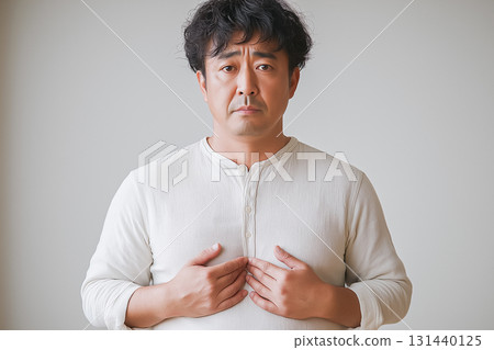 A middle-aged man with his hand on his chest and an anxious expression worried about his health 131440125