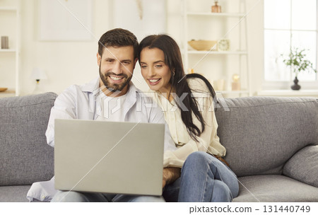 Happy laughing young couple watching laptop screen sofa sitting to enjoy funny movie, planning  131440749
