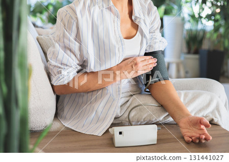Senior woman measuring blood pressure with electronic monitor at home, health check concept Senior woman measuring blood pressure with electronic monitor at home, health check concept 131441027
