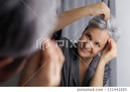 An adult well-groomed beautiful woman of age during menopause with gray hair examines the amount An adult well-groomed beautiful woman of age during menopause with gray hair examines the amount 131441085