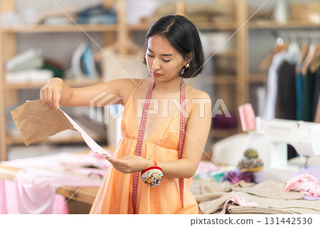 Portrait of positive girl tailor in sewing workshop Portrait of positive girl tailor in sewing workshop 131442530
