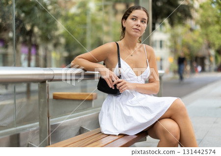 Young woman sitting at a bus stop Young woman sitting at a bus stop 131442574