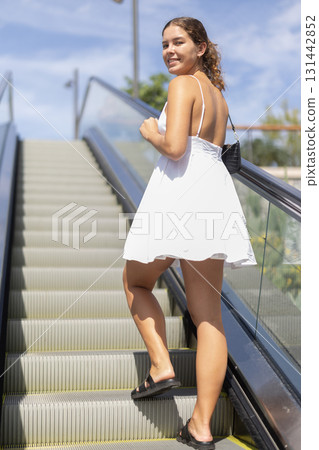 Young girl going up on moving staircase Young girl going up on moving staircase 131442852